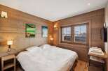 Experience the cozy charm of this bedroom, featuring warm wooden walls and a comfortable bed.
