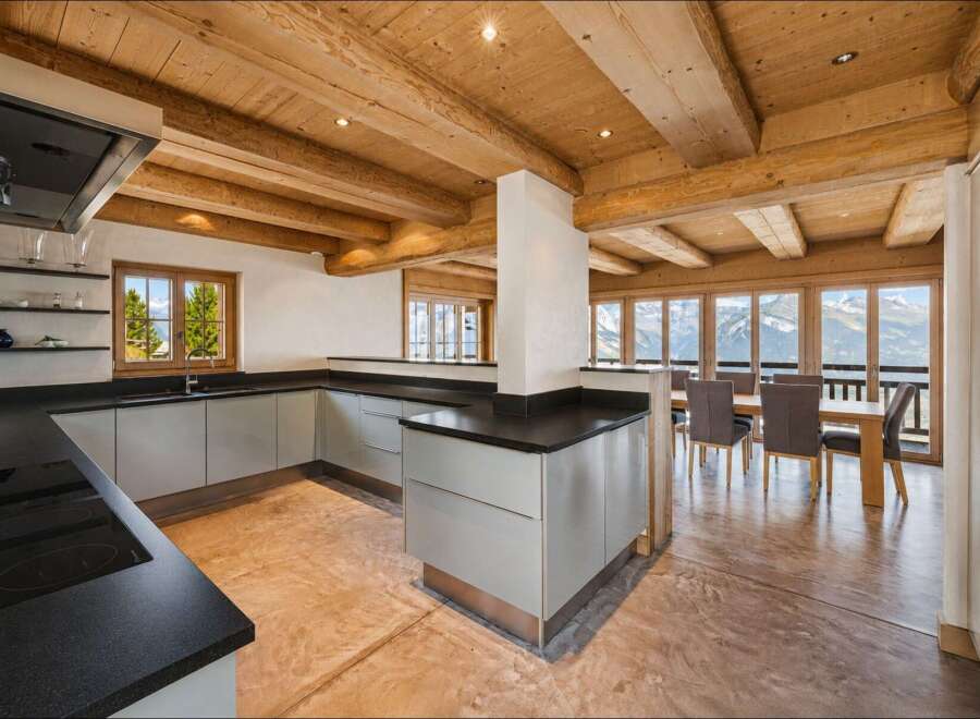 Experience luxury mountain living in this stunning kitchen and dining area, featuring a modern L-shaped kitchen with sleek cabinetry and a spacious island.