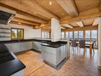 Experience luxury mountain living in this stunning kitchen and dining area, featuring a modern L-shaped kitchen with sleek cabinetry and a spacious island.