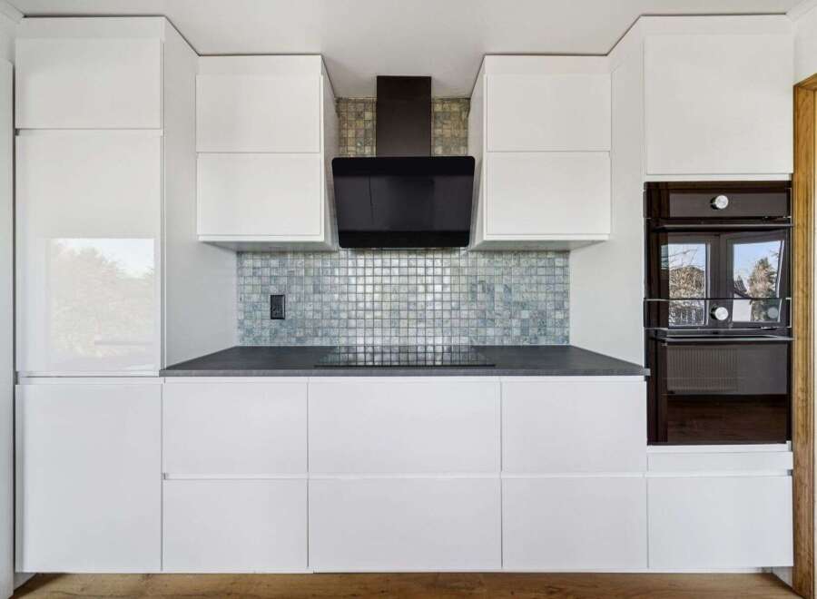 This modern kitchen boasts sleek white cabinetry, offering ample storage and a clean aesthetic.