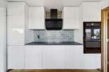 This modern kitchen boasts sleek white cabinetry, offering ample storage and a clean aesthetic.