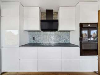 This modern kitchen boasts sleek white cabinetry, offering ample storage and a clean aesthetic.