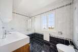 This stunning bathroom features a modern design with sleek white tiles and a contrasting black tiled floor.