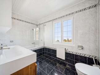 This stunning bathroom features a modern design with sleek white tiles and a contrasting black tiled floor.