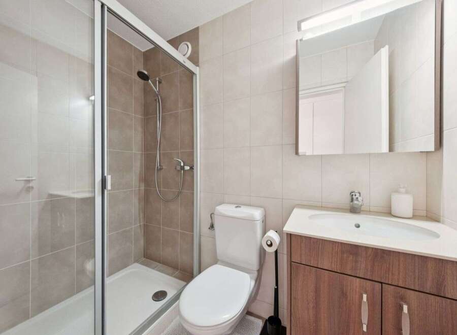 This modern bathroom features a sleek glass shower enclosure, perfect for a refreshing start to your day.
