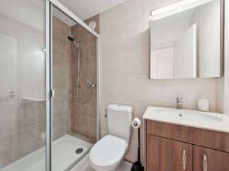 This modern bathroom features a sleek glass shower enclosure, perfect for a refreshing start to your day.