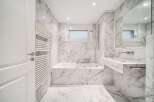 This luxurious bathroom boasts stunning marble finishes throughout, creating a spa-like ambiance.
