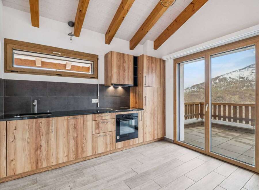This stunning kitchen boasts a modern design with wooden cabinetry and sleek black countertops, creating a warm and inviting atmosphere.