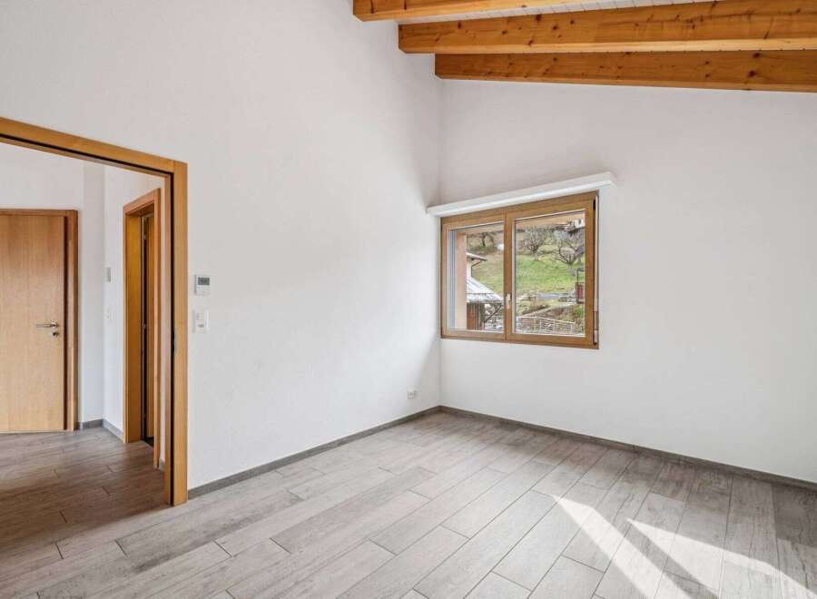 Discover this bright and airy room, featuring a modern design with light-colored wooden floors and pristine white walls.