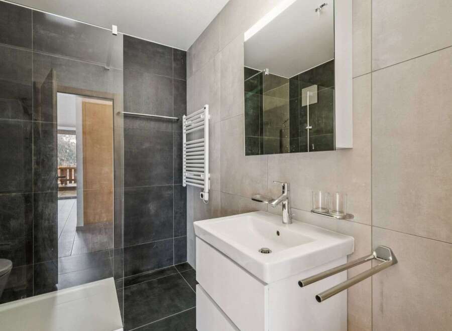 This modern bathroom features sleek gray tiles and a minimalist design.