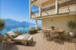 Enjoy breathtaking views from this stunning property! This outdoor space features a comfortable chaise lounge, a dining table, and lush greenery, perfect for relaxation and entertaining.