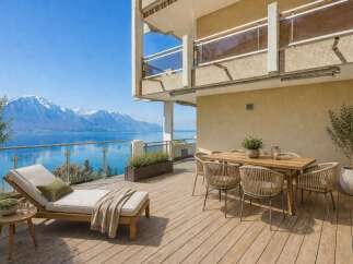 Enjoy breathtaking views from this stunning property! This outdoor space features a comfortable chaise lounge, a dining table, and lush greenery, perfect for relaxation and entertaining.