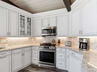 This stunning kitchen boasts elegant white cabinetry with intricate detailing, complemented by a beautiful marble countertop.