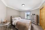 Step into this inviting bedroom, featuring a cozy bed with a stylish headboard and a warm, neutral color palette.