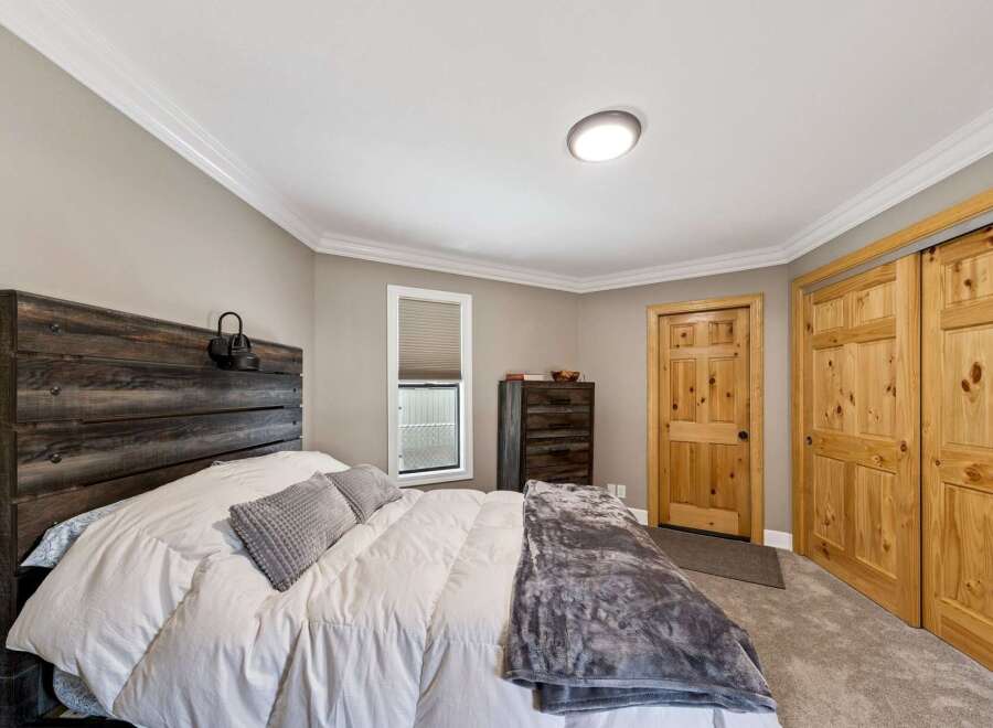Step into this inviting bedroom, featuring a rustic wooden headboard that adds a touch of warmth and character.