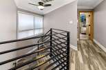 This stunning property features a modern staircase with sleek black railings, leading to a hallway with beautiful wood-look flooring.