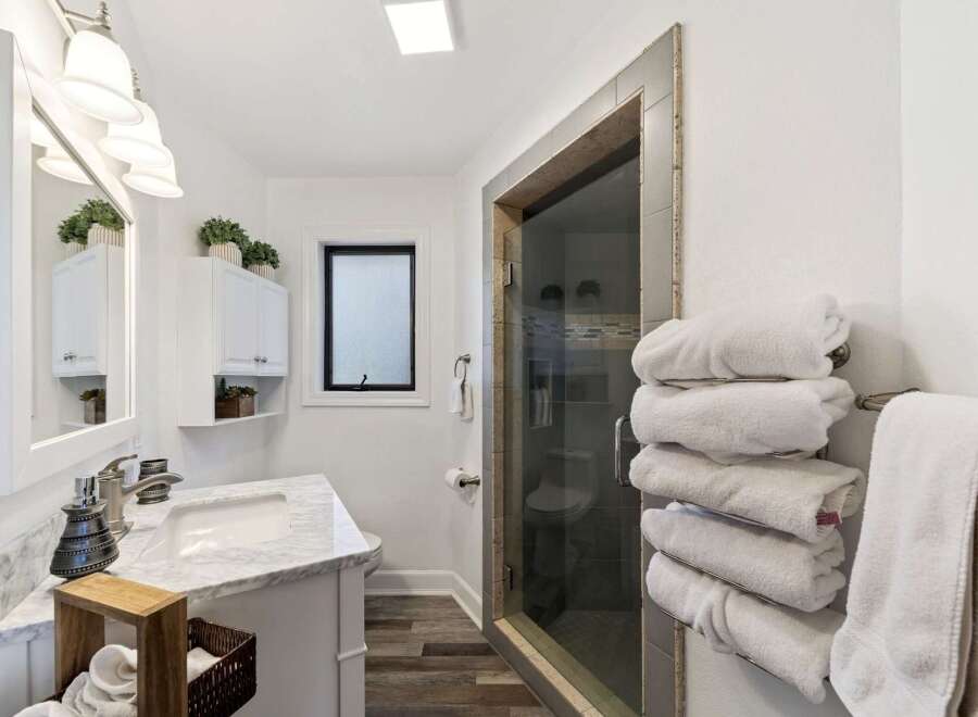 Step into this beautifully designed bathroom, featuring a modern vanity with a marble countertop and a sleek sink.