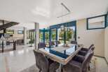Experience luxury living in this stunning property, featuring a modern dining area with a sleek glass table and comfortable seating.