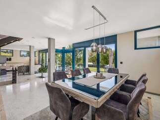 Experience luxury living in this stunning property, featuring a modern dining area with a sleek glass table and comfortable seating.