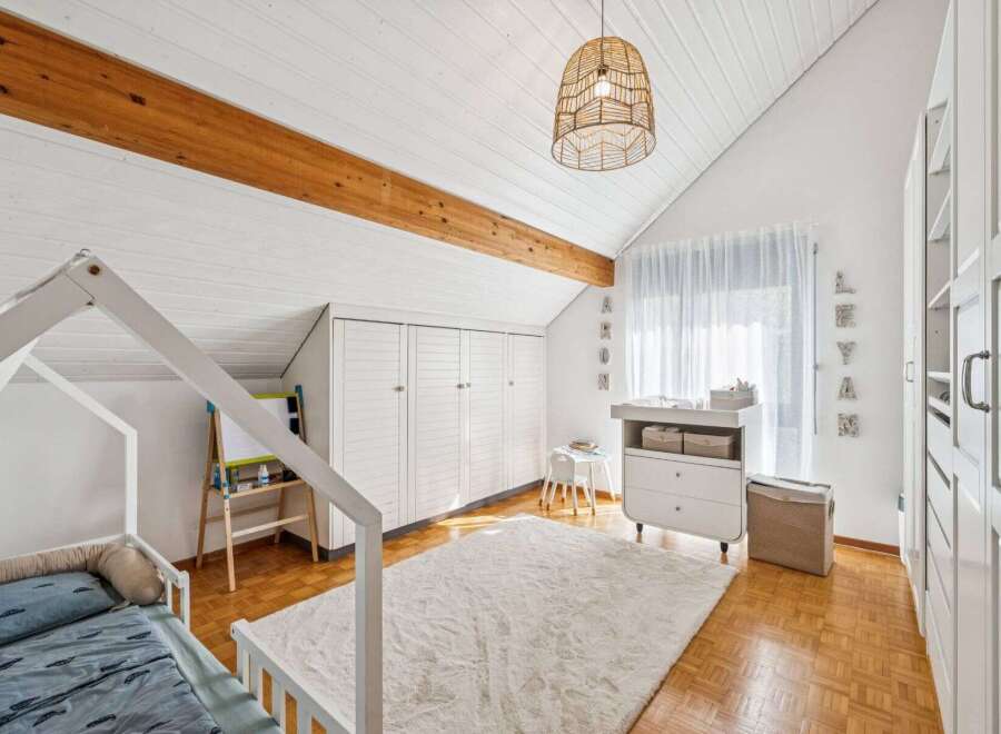 This charming nursery features a cozy house-shaped bed, a plush rug, and a stylish changing table.