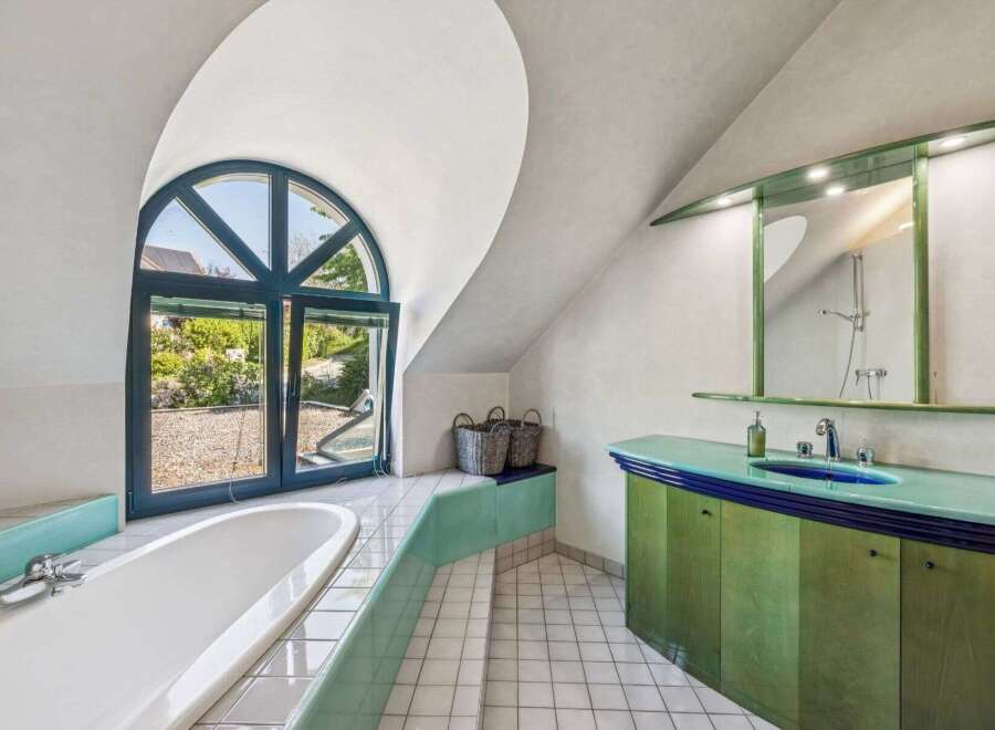 This stunning bathroom boasts a unique design with a large, arched window that floods the space with natural light.