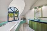 This stunning bathroom boasts a unique design with a large, arched window that floods the space with natural light.