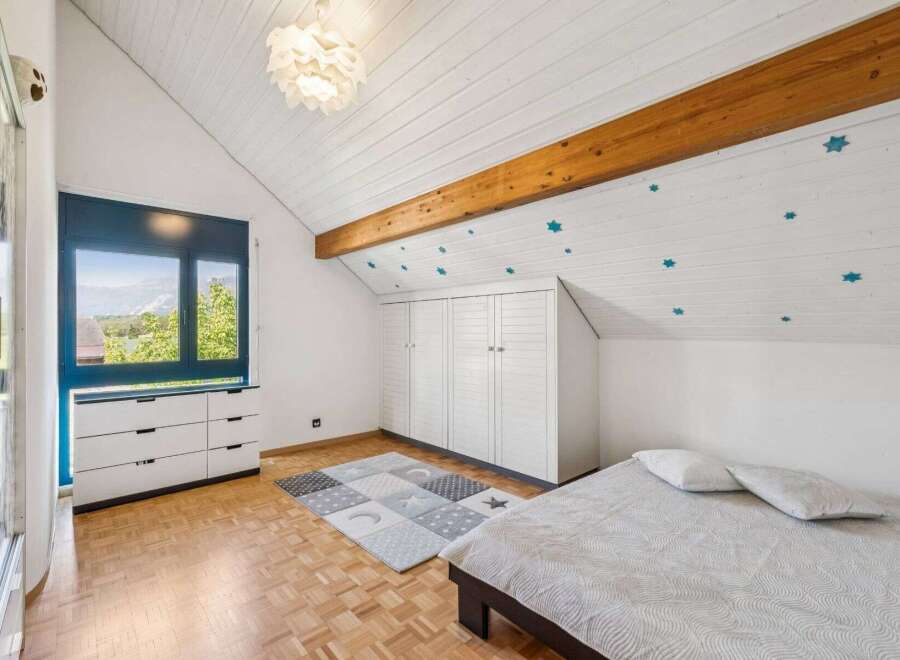 This charming bedroom features a unique sloped ceiling with wooden beams and star-shaped decorations, creating a cozy and inviting atmosphere.