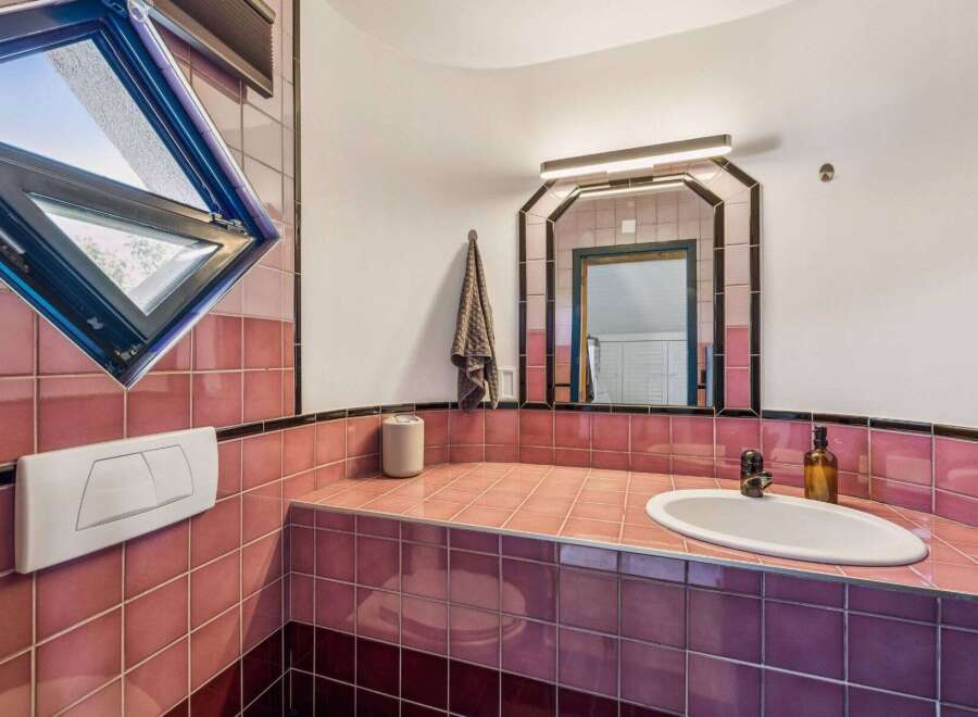 Step into this unique bathroom featuring a striking pink tiled design.