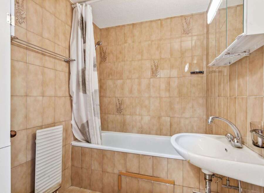This bathroom features a classic design with warm-toned tiles, creating a cozy atmosphere.