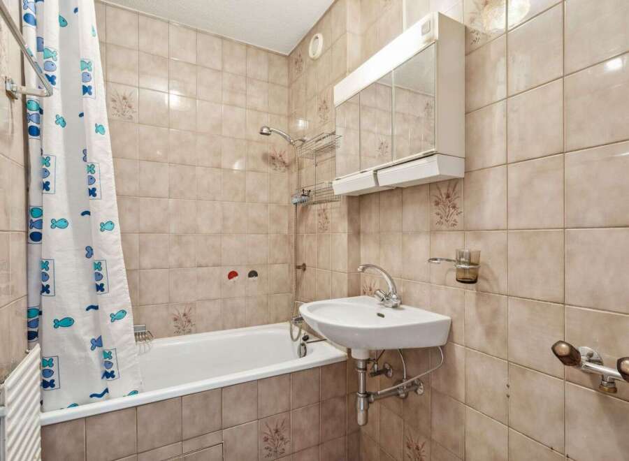 This bathroom features a classic design with tiled walls and a bathtub.