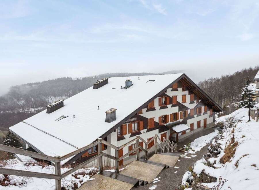 Nestled in a snowy landscape, this charming property boasts a traditional chalet design with a steeply pitched roof.
