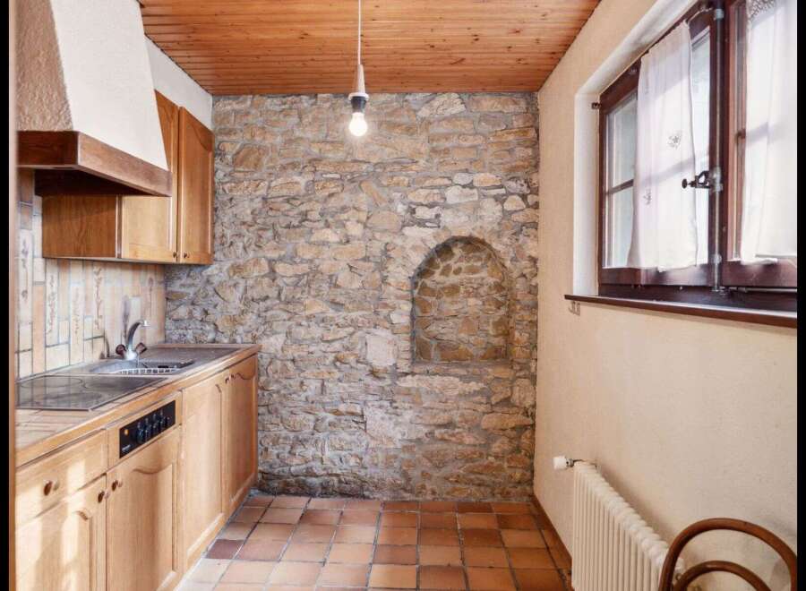 This charming kitchen features a rustic stone wall, adding character and warmth to the space.