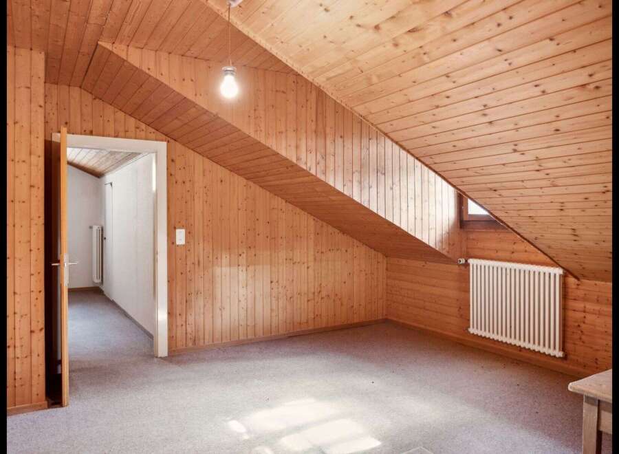 This charming attic space boasts a unique design with its sloped wooden ceiling and walls, creating a cozy and inviting atmosphere.