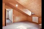This charming attic space boasts a unique design with its sloped wooden ceiling and walls, creating a cozy and inviting atmosphere.