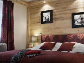 This cozy bedroom features a rustic wooden wall and a comfortable bed with a patterned headboard.