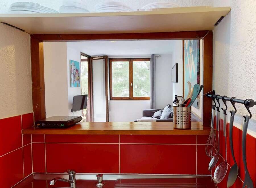 Discover this charming property featuring a well-equipped kitchen with a stylish red tile backsplash and a convenient pass-through window.