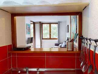 Discover this charming property featuring a well-equipped kitchen with a stylish red tile backsplash and a convenient pass-through window.