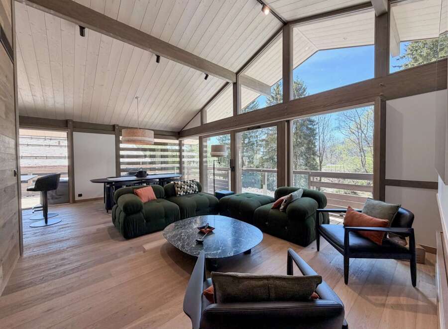 Experience luxury living in this stunning property, featuring a spacious living area with a vaulted ceiling and expansive windows that offer breathtaking views of the surrounding landscape.