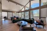 Experience luxury living in this stunning property, featuring a spacious living area with a vaulted ceiling and expansive windows that offer breathtaking views of the surrounding landscape.