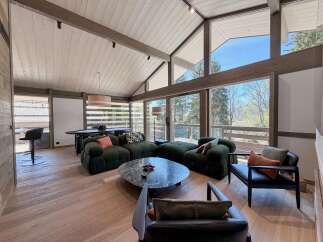 Experience luxury living in this stunning property, featuring a spacious living area with a vaulted ceiling and expansive windows that offer breathtaking views of the surrounding landscape.