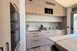 This modern kitchen boasts sleek, light wood cabinetry and a minimalist design, perfect for contemporary living.