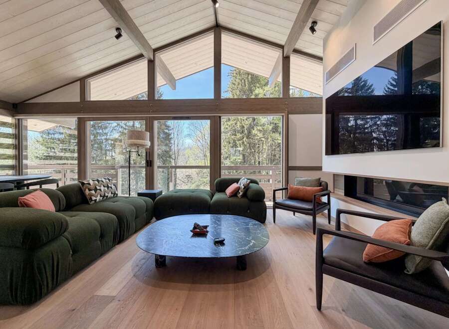 Experience luxury living in this stunning property featuring a spacious living area with a vaulted ceiling and expansive windows that offer breathtaking views of the surrounding nature.