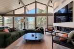 Experience luxury living in this stunning property featuring a spacious living area with a vaulted ceiling and expansive windows that offer breathtaking views of the surrounding nature.