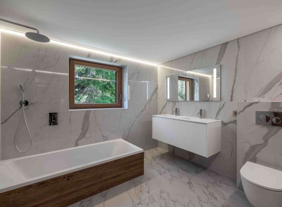 Experience luxury in this modern bathroom featuring stunning marble-effect tiles and a sleek, minimalist design.