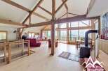 Experience the charm of this stunning property, featuring a spacious living area with exposed wooden beams and large windows offering breathtaking mountain views.