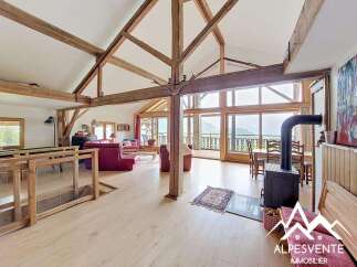 Experience the charm of this stunning property, featuring a spacious living area with exposed wooden beams and large windows offering breathtaking mountain views.
