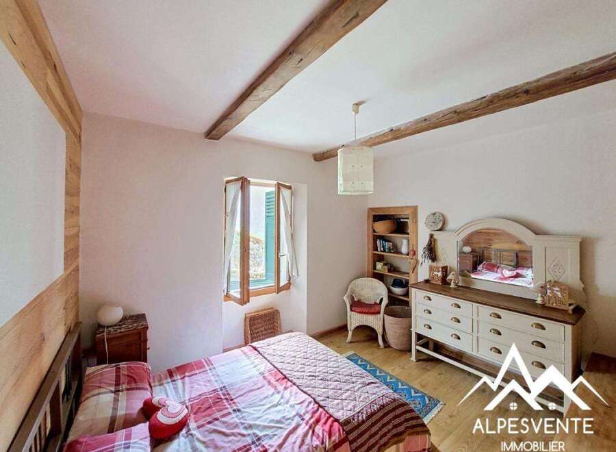 Discover the charm of this cozy bedroom, featuring rustic wooden beams and a warm, inviting atmosphere.