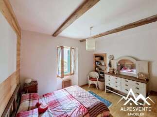 Discover the charm of this cozy bedroom, featuring rustic wooden beams and a warm, inviting atmosphere.