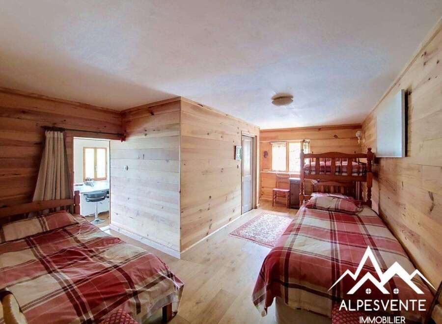 Discover this charming bedroom featuring rustic wooden walls and cozy bedding.