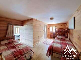 Discover this charming bedroom featuring rustic wooden walls and cozy bedding.